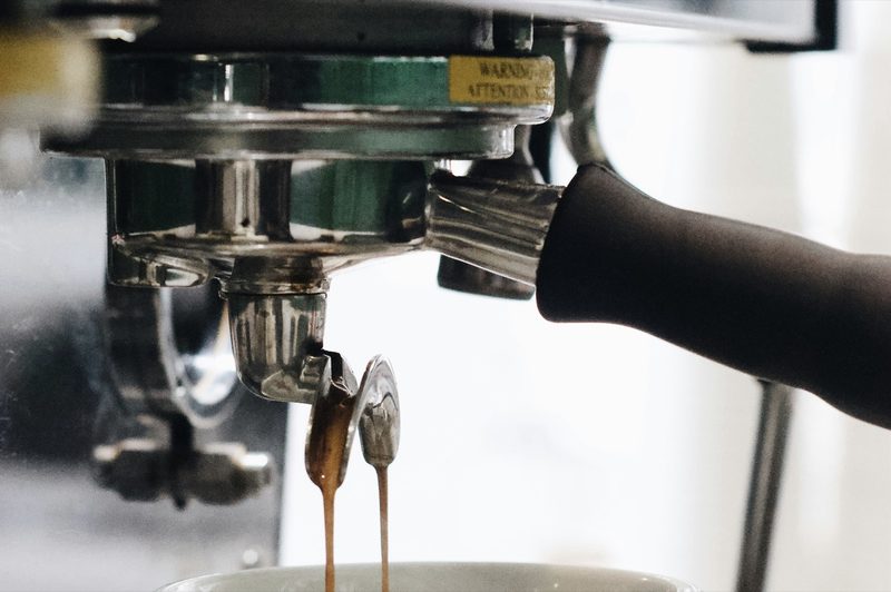 Two espresso streams running from a naked portafilter into a cup below.